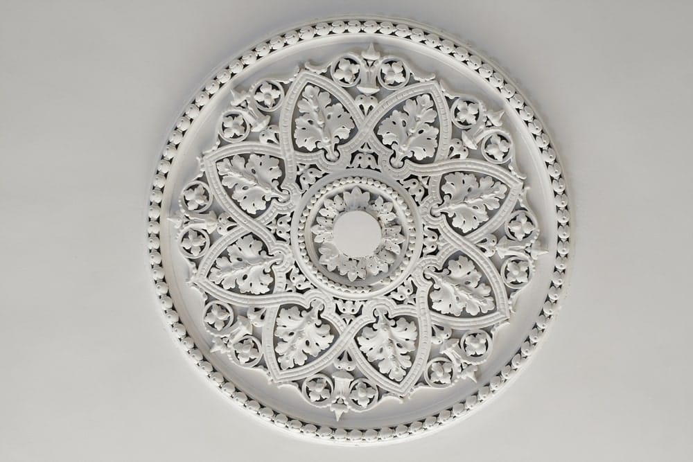 Decorative ceiling medallion with intricate floral carvings in white.