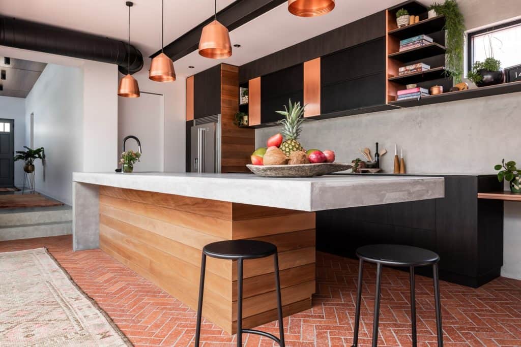 Stylish ceiling with copper pendant lights and black duct, blending contemporary aesthetics with functional lighting.