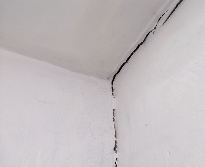 Close-up of ceiling crack caused by structural shift, requiring professional ceiling repair.