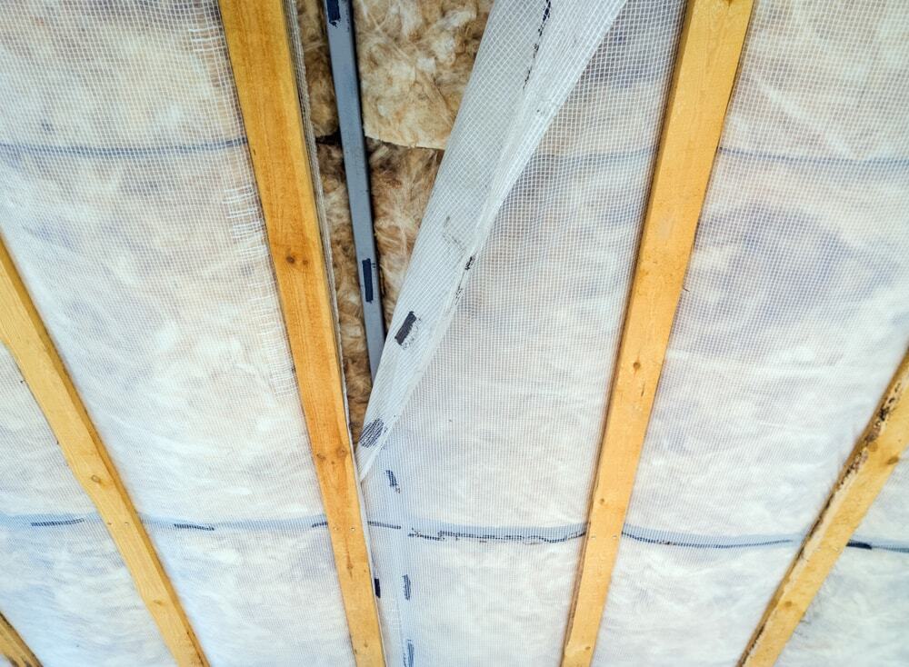 Insulation panels are securely fitted between wooden beams on the ceiling.