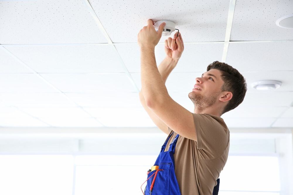 A technician installing a ceiling sensor to enhance space safety and automation.