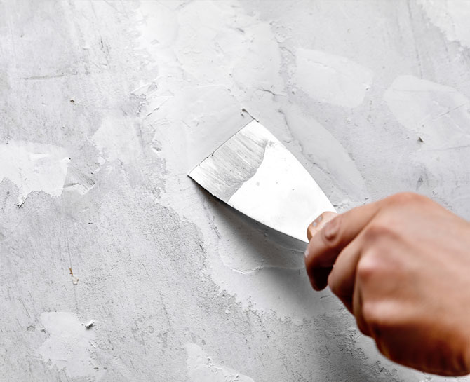 A hand applying fresh plaster to a ceiling surface, emphasizing ceiling repairs and renovation services.