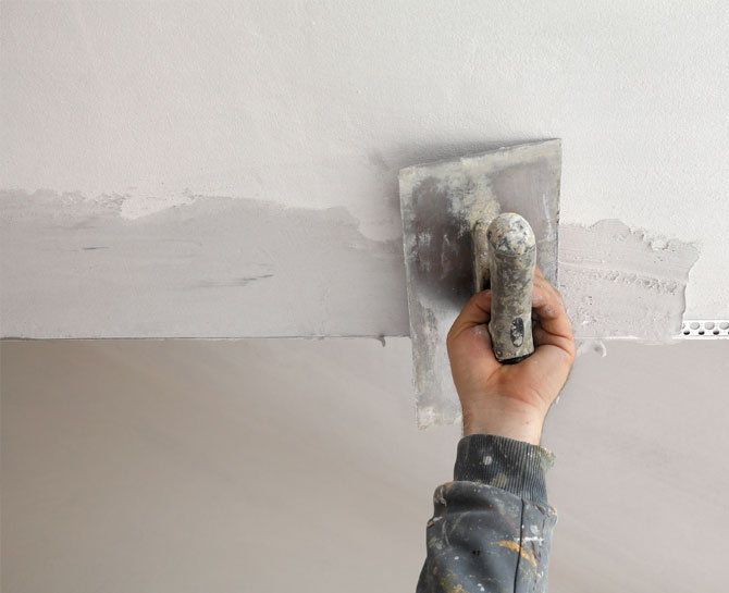 Skilled ceiling plasterer applying plaster to smooth ceiling surface in Australia.