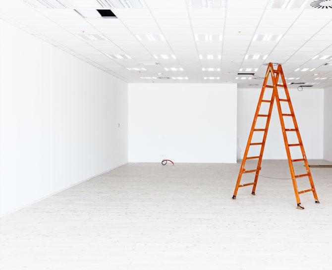 Bright white ceiling with suspended tiles, repair ladder in a modern interior.